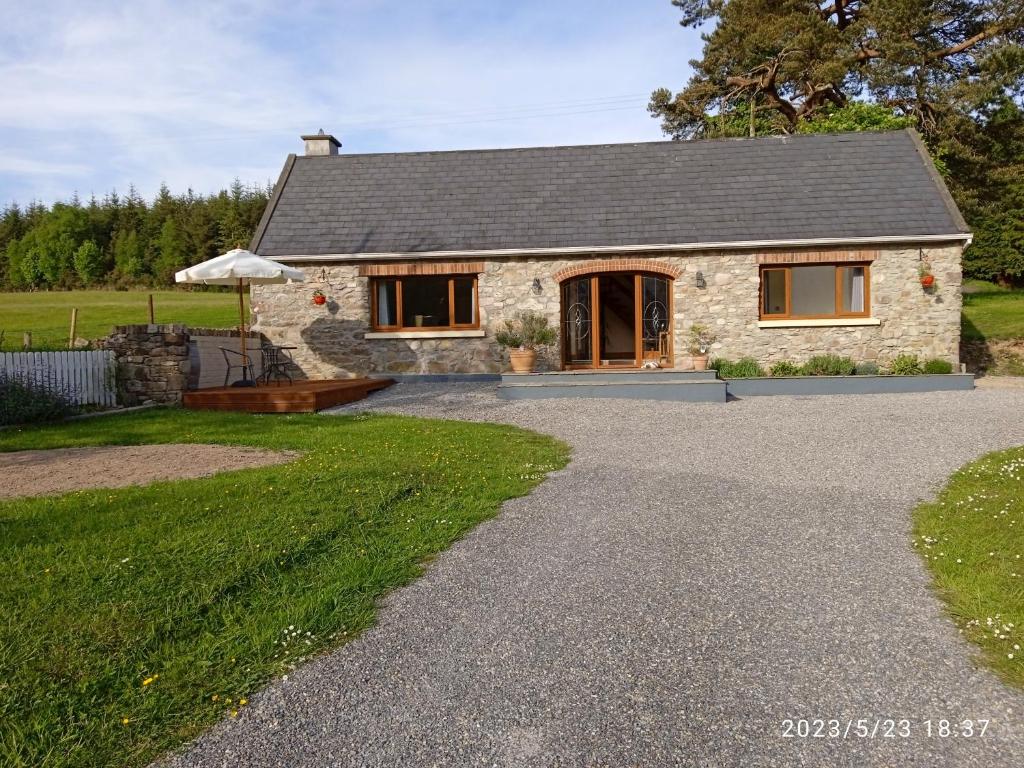 a stone cottage with a gravel driveway at Nire Valley Cottage 