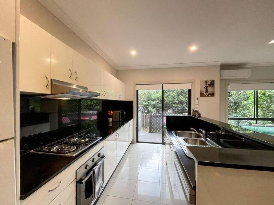 a kitchen with white cabinets and black counter tops at Love Love Love ^^ in Hornsby