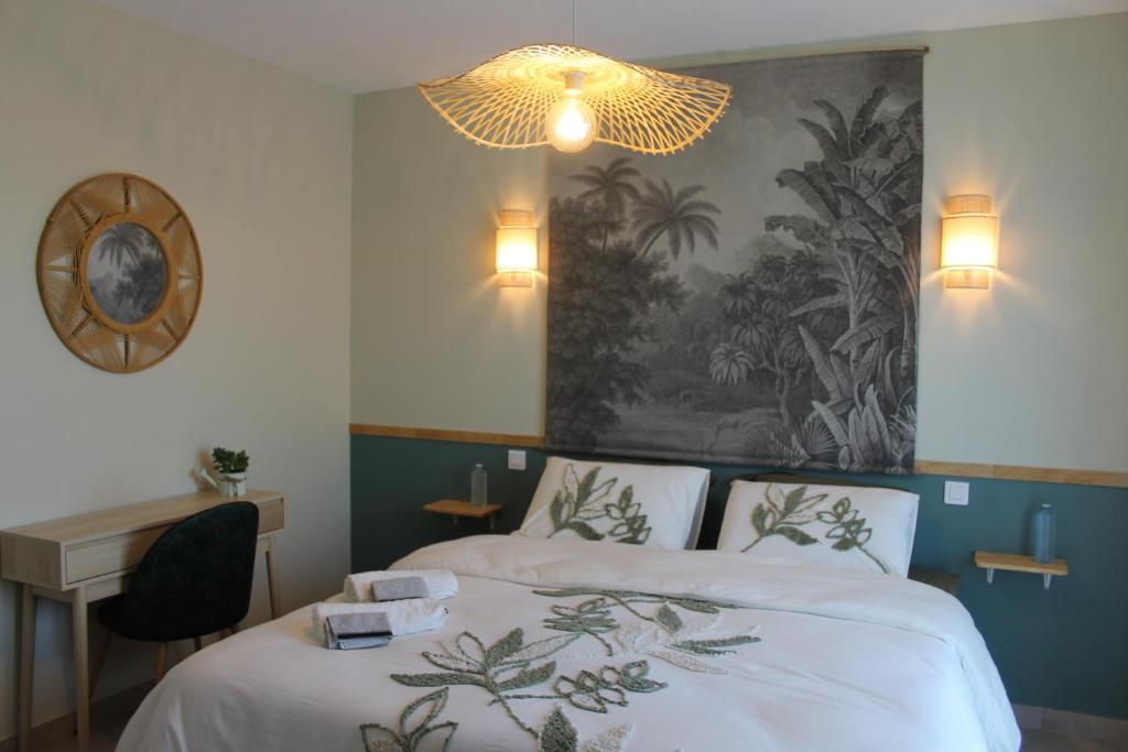 a bedroom with two beds and a desk and a chandelier at La Naillousaine in Nailloux