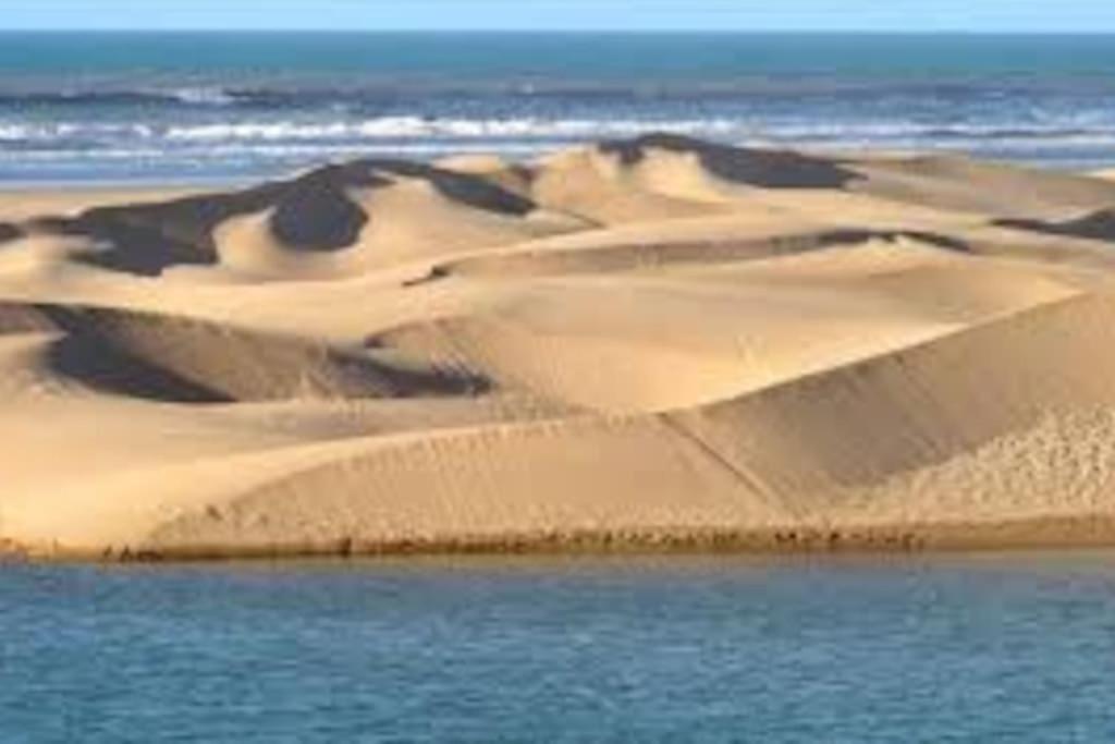 a group of sand dunes next to a body of water at Appartement propre et spacieux Tan Tan Plage El Ouatia in Tan-Tan Plage