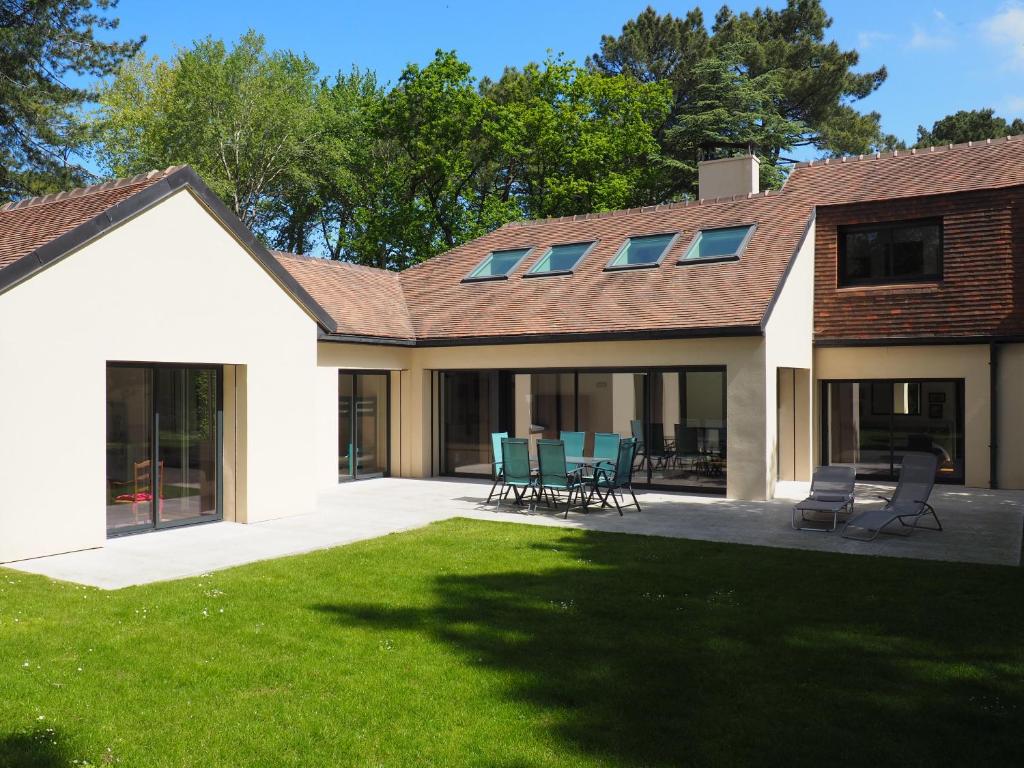 une maison avec une terrasse et des chaises dans la cour dans l'établissement Les Héliades, à Le Touquet-Paris-Plage