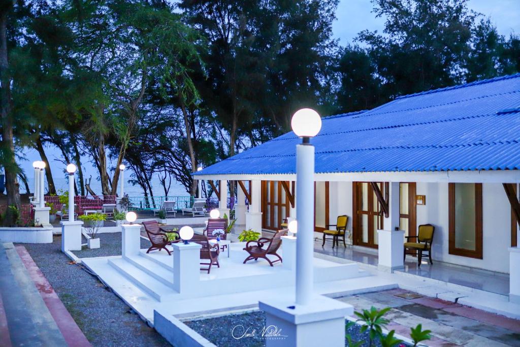 a building with a blue roof with chairs and tables at Ceylonta Beach Resort in Hambantota