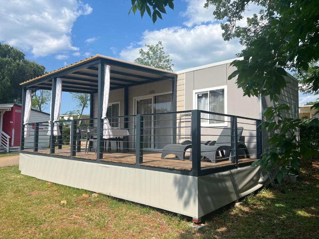 a house with a deck with a table and chairs at Mobile Homes Relax Park Umag in Umag