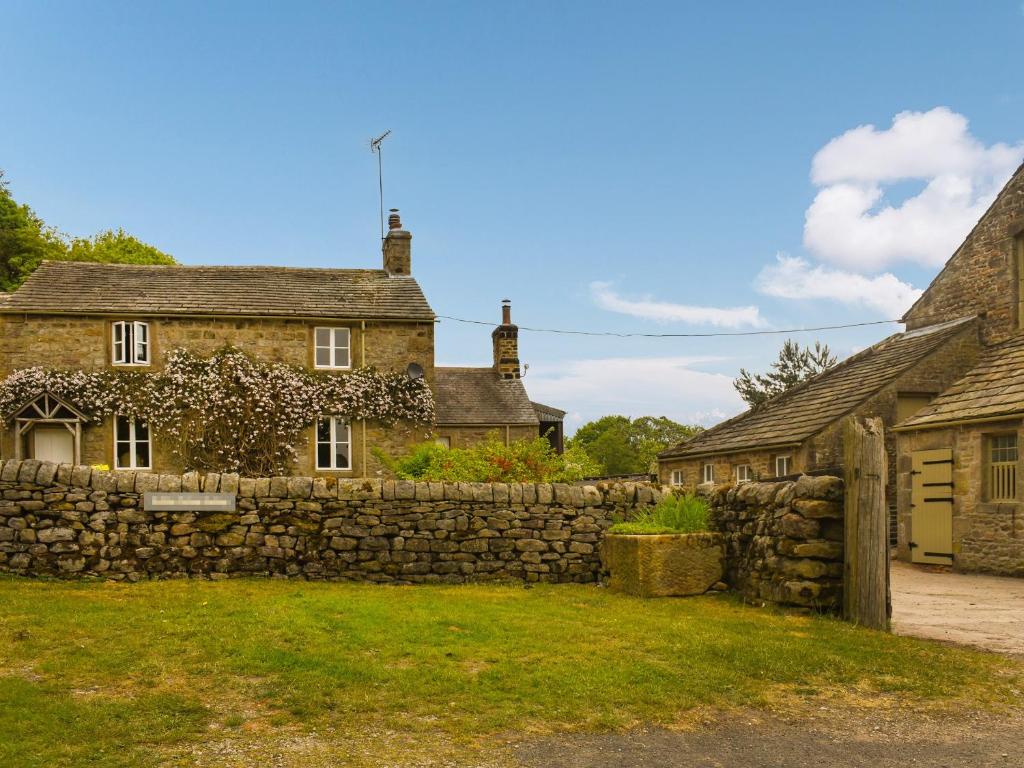 an old stone house with a stone wall at The Shippon in Appletreewick