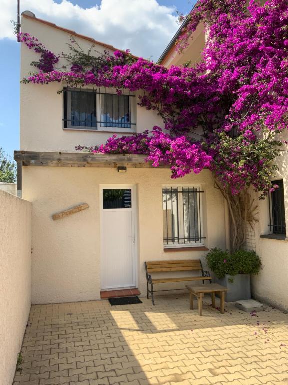 un bâtiment avec des fleurs violettes et un banc dans l'établissement La Perdrix, à Argelès-sur-Mer