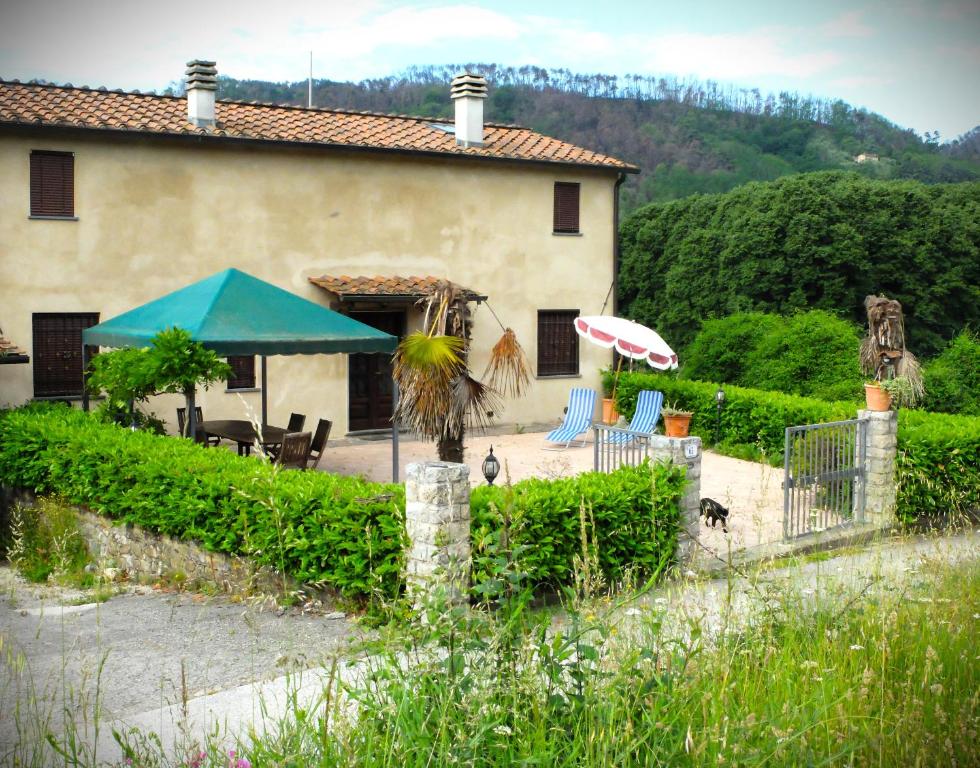 ein Haus mit einer Terrasse, einem Sonnenschirm und Stühlen in der Unterkunft La Cheta in Monsagrati