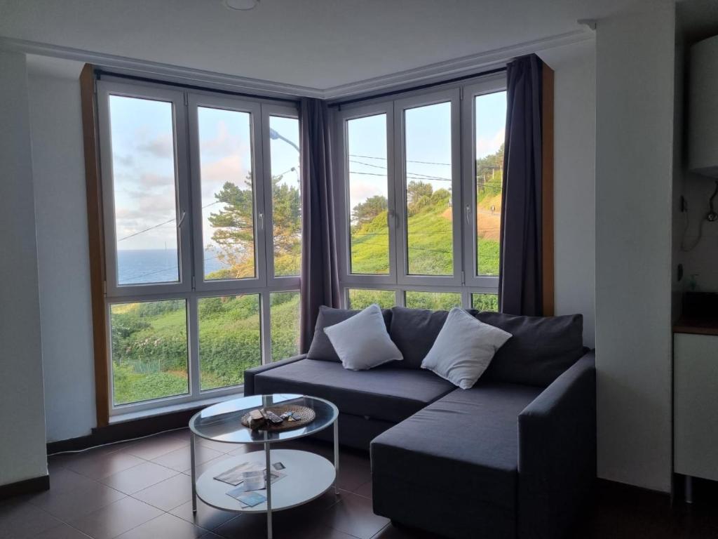 a living room with a couch and a large window at Casa As Neves - 1B Gran Ventanal in Malpica