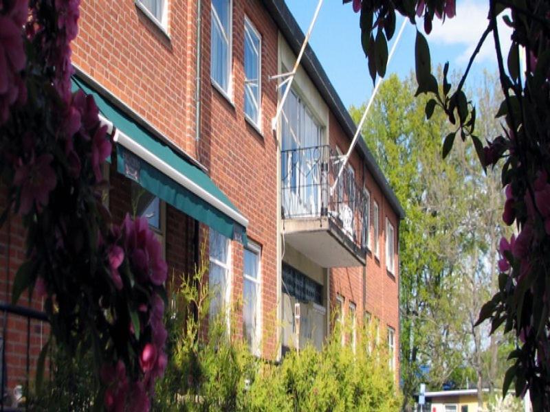 a red brick building with a balcony and flowers at Vingåker Hotell in Vingåker