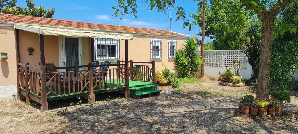 una pequeña casa con un porche con un árbol en Casa Fernandet 3 bedrooms house, en Sueca