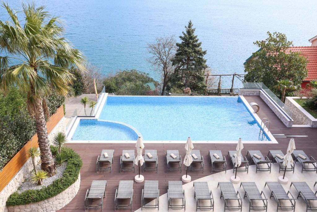 a swimming pool with chairs and the ocean in the background at Bellezza Resort & SPA in Kotor