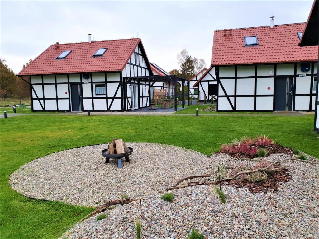 a park with two black and white buildings and a bench at Domki Trzy - 3 in Smołdziński Las