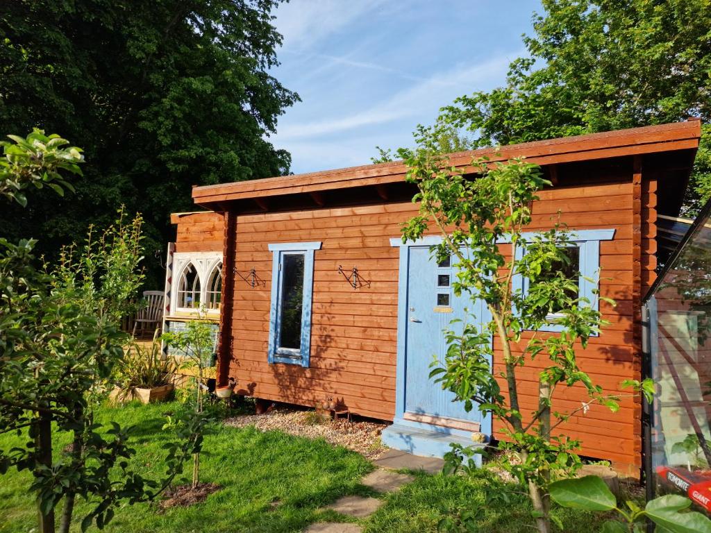 a small wooden shed with a blue door at Piddle Puddle Cabin in Dorchester