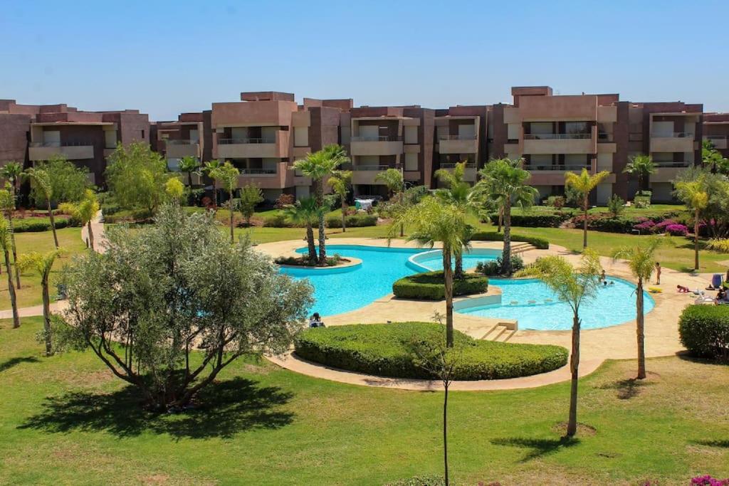 an apartment complex with a swimming pool in a park at BEL APPART FONCTIONNEL PRESTIGIA GOLF MARRAKECH in Marrakesh