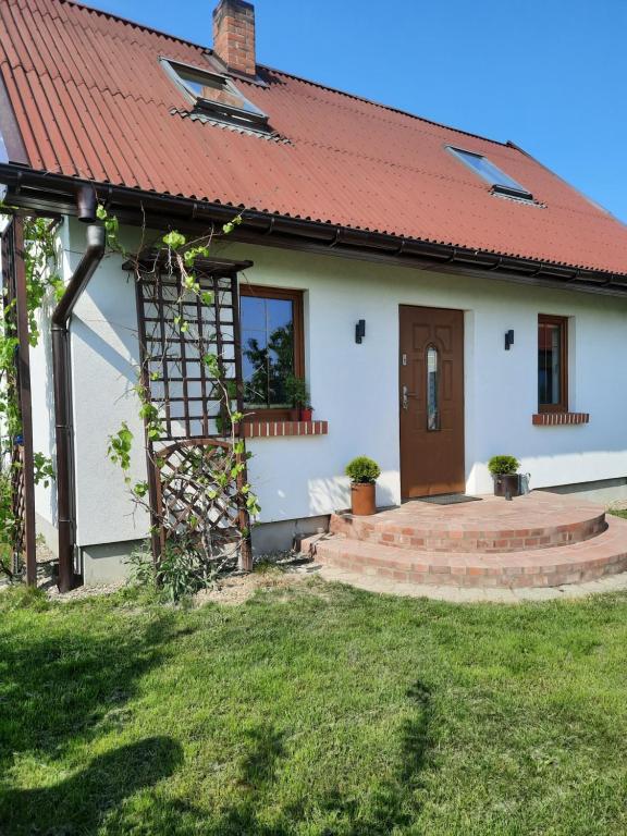 une petite maison blanche avec un toit rouge dans l'établissement Wierzbowy zakątek Kąty Rybackie, à Kąty Rybackie