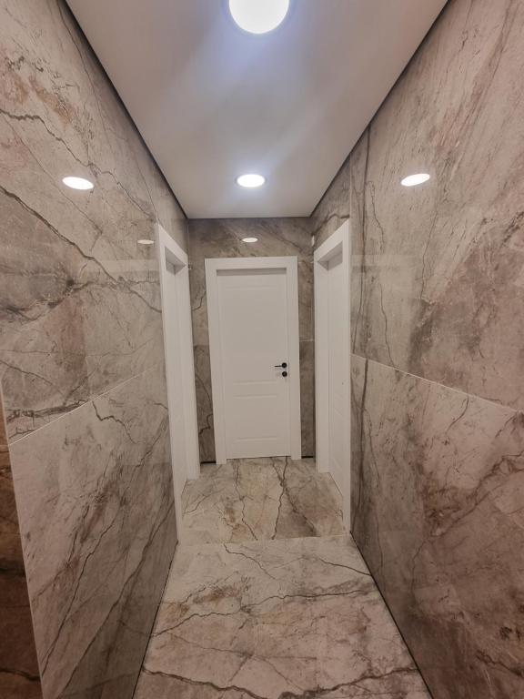 d'un couloir avec des murs en marbre et une porte blanche. dans l'établissement הברון baron, à Rishon LeẔiyyon
