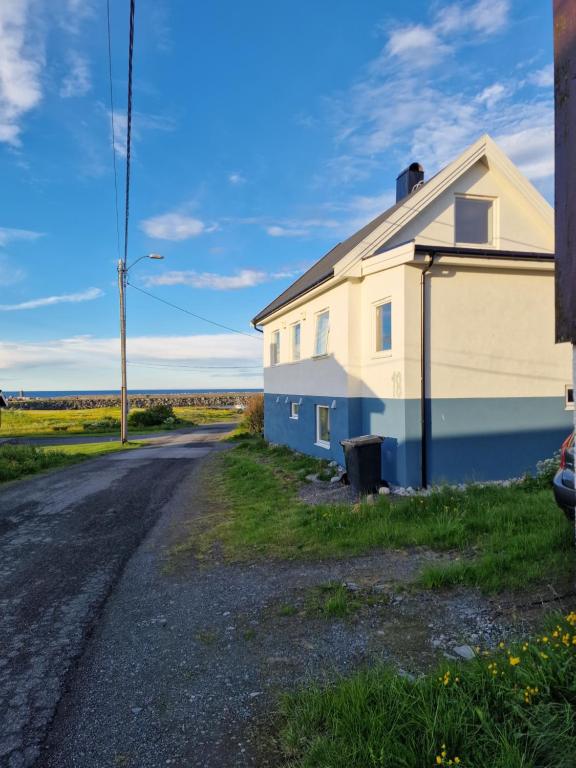 uma casa branca e azul ao lado de uma estrada em Liten leilighet i Berlevåg em Berlevåg