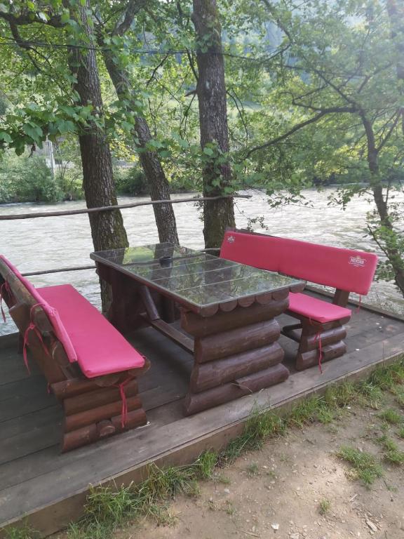 a picnic table and two red chairs on a deck at Golden Dream in Jajce