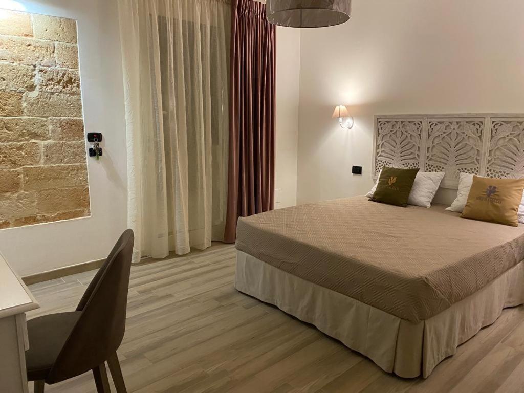 een slaapkamer met een bed en een bureau met een stoel bij B&B villa Gallo in Torre Squillace