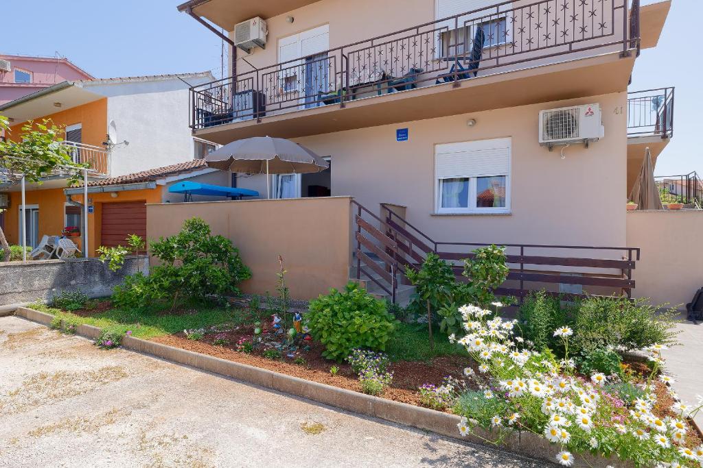 een huis met een paraplu en bloemen ervoor bij Apartman Mishel 1 Fazana in Fažana