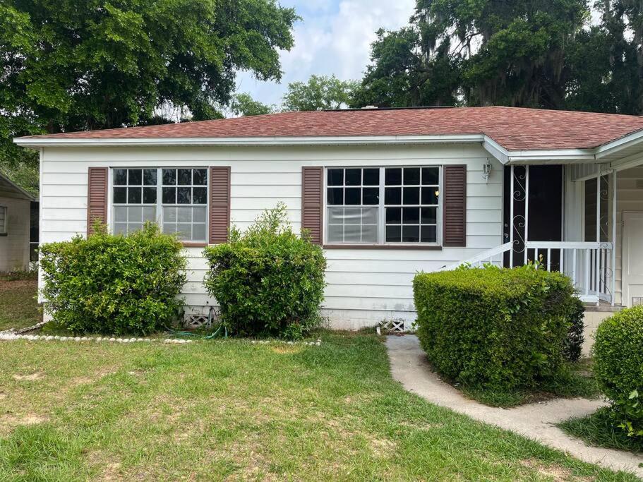 una casa blanca con arbustos delante en Mid Century Style Cottage Near Historic Downtown en Eustis