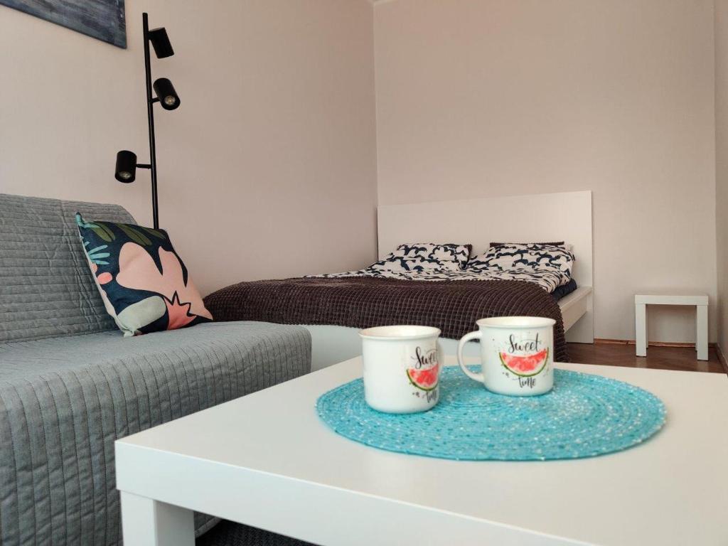 two coffee cups sitting on a table in a living room at Słoneczna kawalerka in Gdańsk