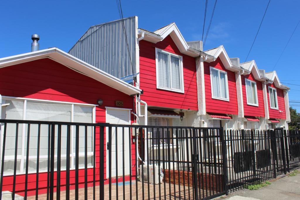 a red house with a fence in front of it at Departamentos Egaña in Puerto Montt