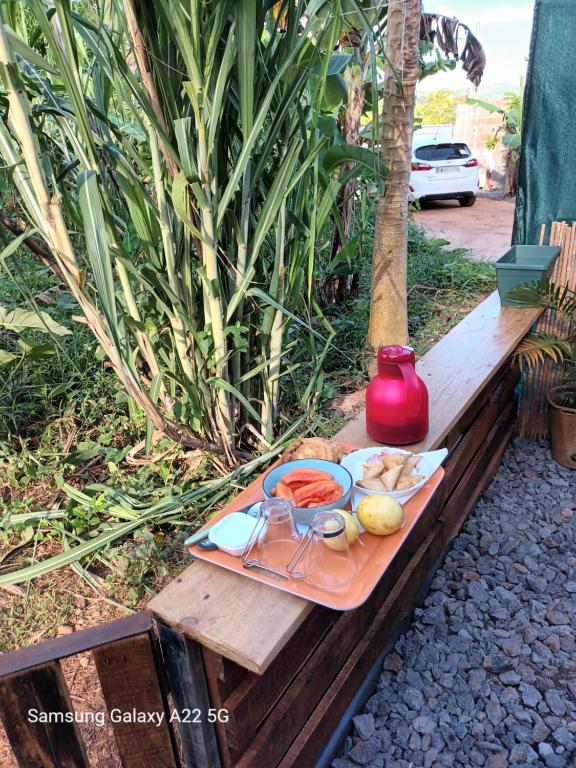 a tray of food on a wooden bench with a vase at Chez Mkoudou in Ouangani