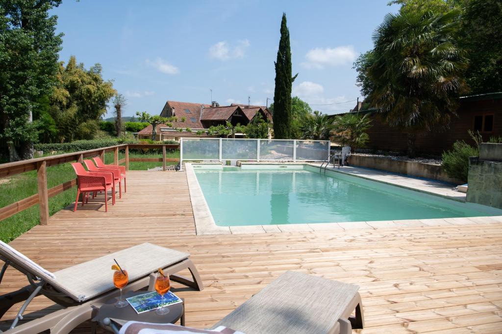 uma piscina com cadeiras e um deque de madeira em Le Moulin du Porteil em Campagne