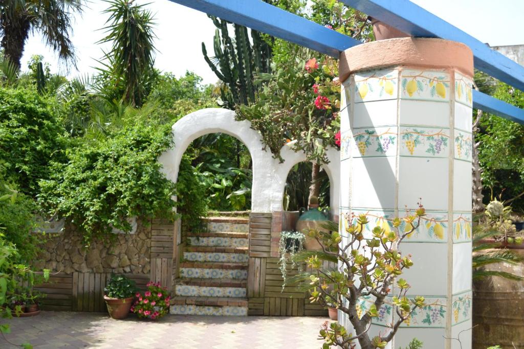 a garden with an arch and stairs with flowers at Piccolo Tirreno Hotel Residence in Procida