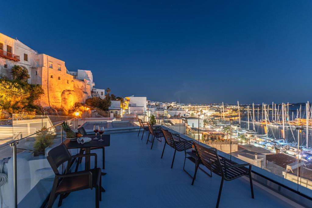 balcón con sillas y mesas y vistas al puerto en Mariet Naxos Spa & Suites en Naxos