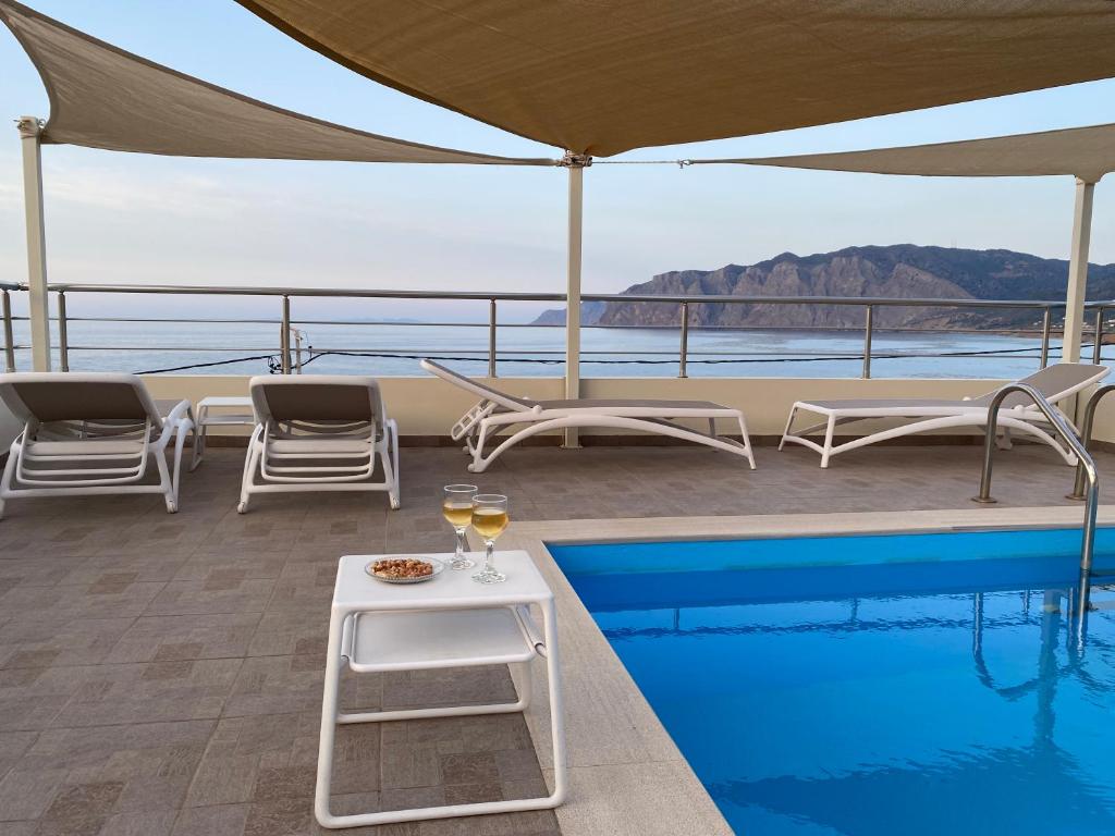 a swimming pool with a table and glasses of wine at Anemos-Halcyon-Eirene in Mochlos