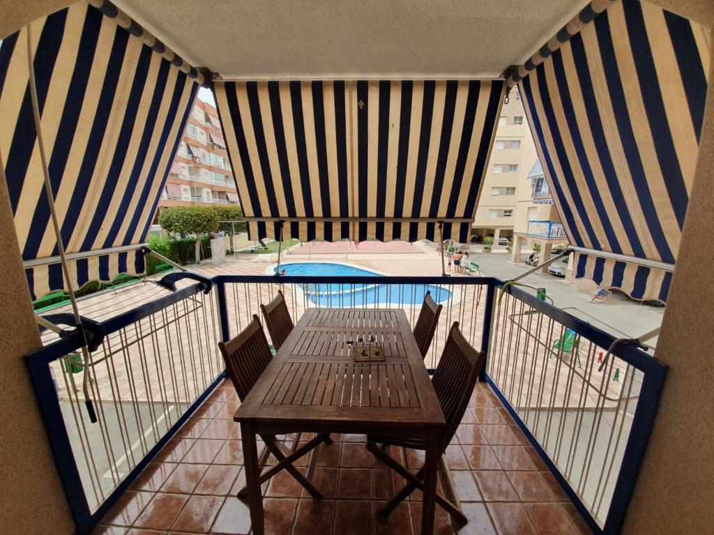 balcón con mesa de madera y sillas y piscina en Mediterraneo, en Santa Pola