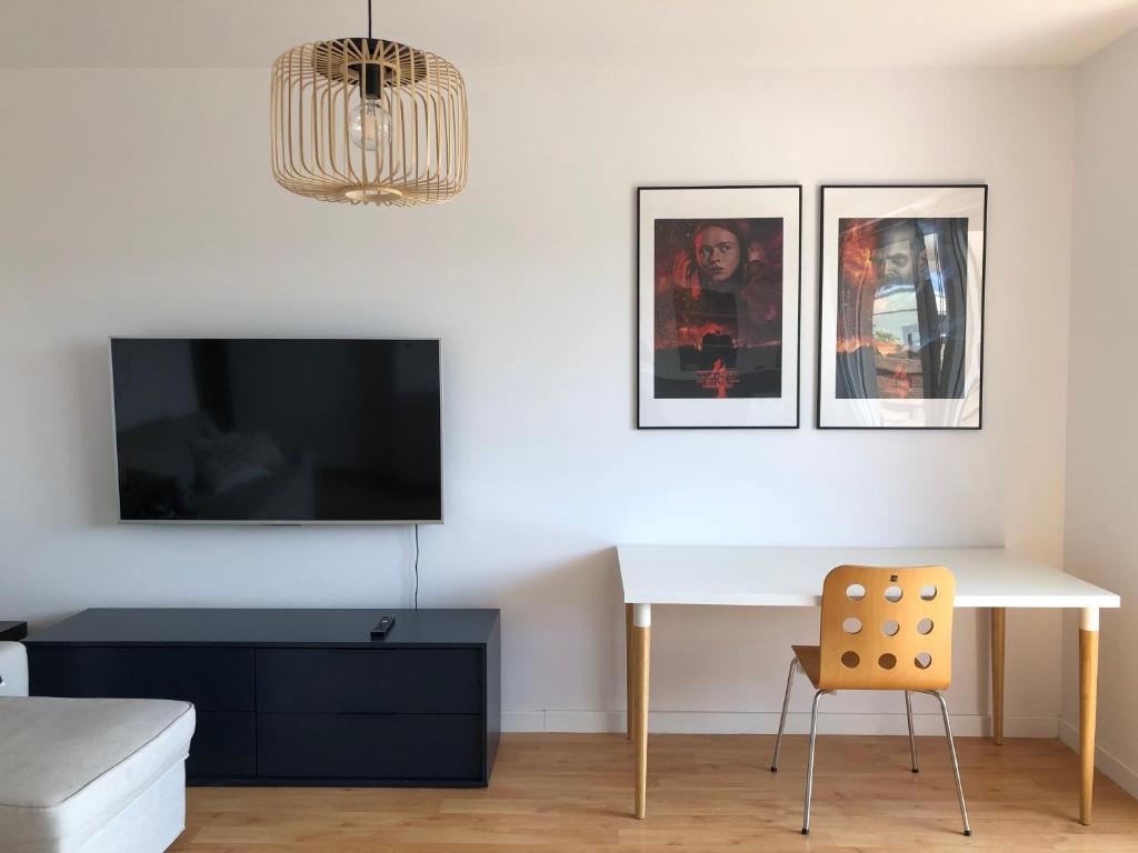 salon z biurkiem i telewizorem na ścianie w obiekcie Bałtycki Chill - apartament z możliwością Home Office w mieście Gdynia