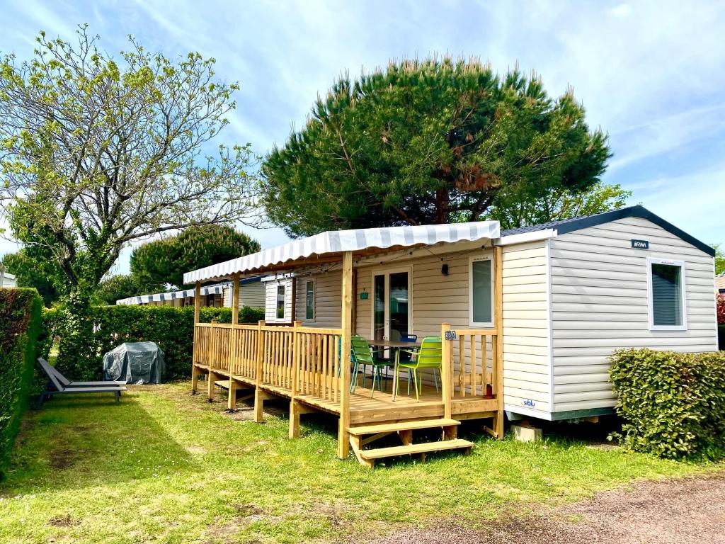 a yellow and white tiny house with a large deck at Mobil Home excellence 6 personnes au camping Mer et Soleil, Saint George d'Oléron in Les Sables Vignier