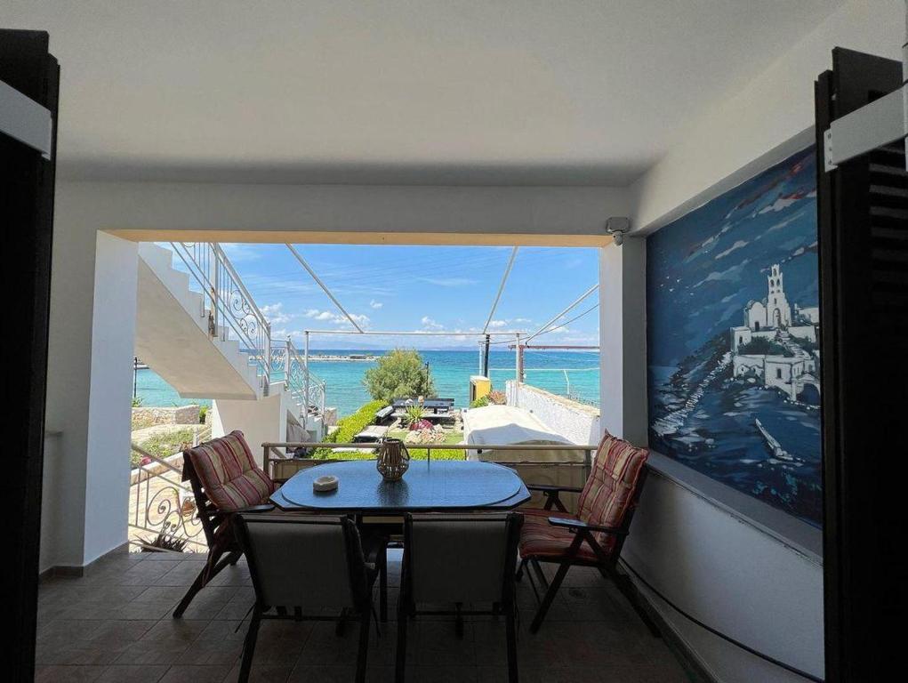 una sala da pranzo con tavolo, sedie e vista sull'oceano di Ελένη a Megalochori (Isola di Agistri)