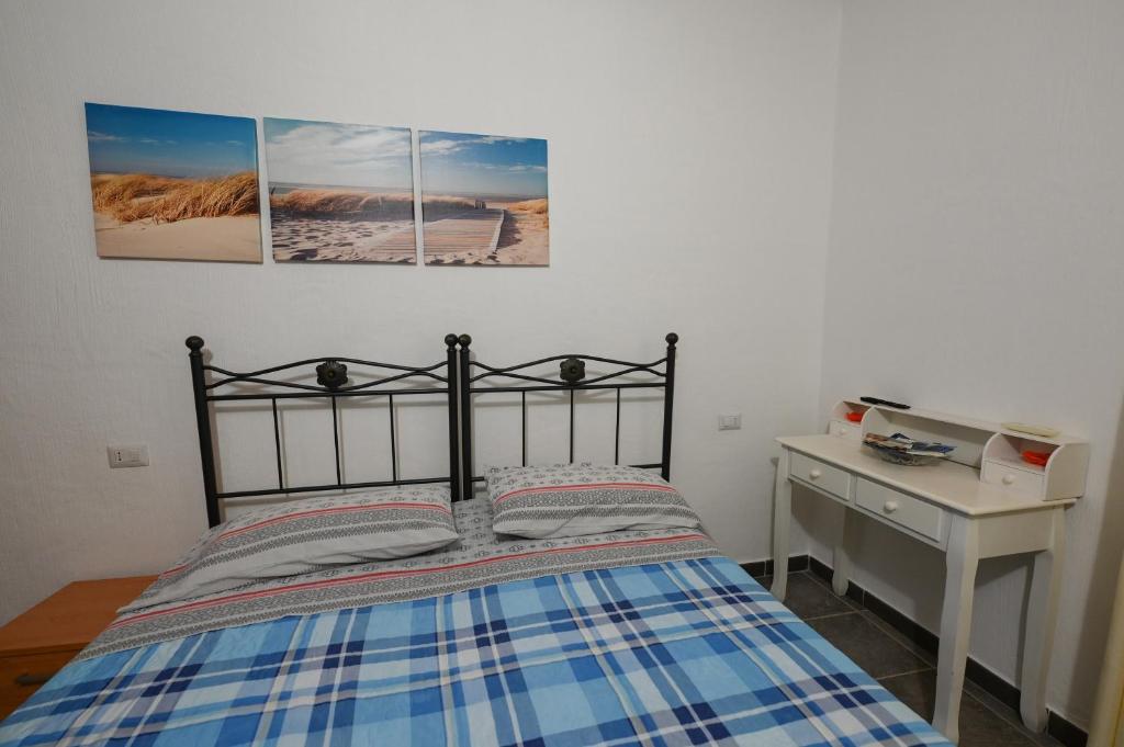 a bedroom with a bed and a desk with two pictures on the wall at B&B Su Neulagi in Triei