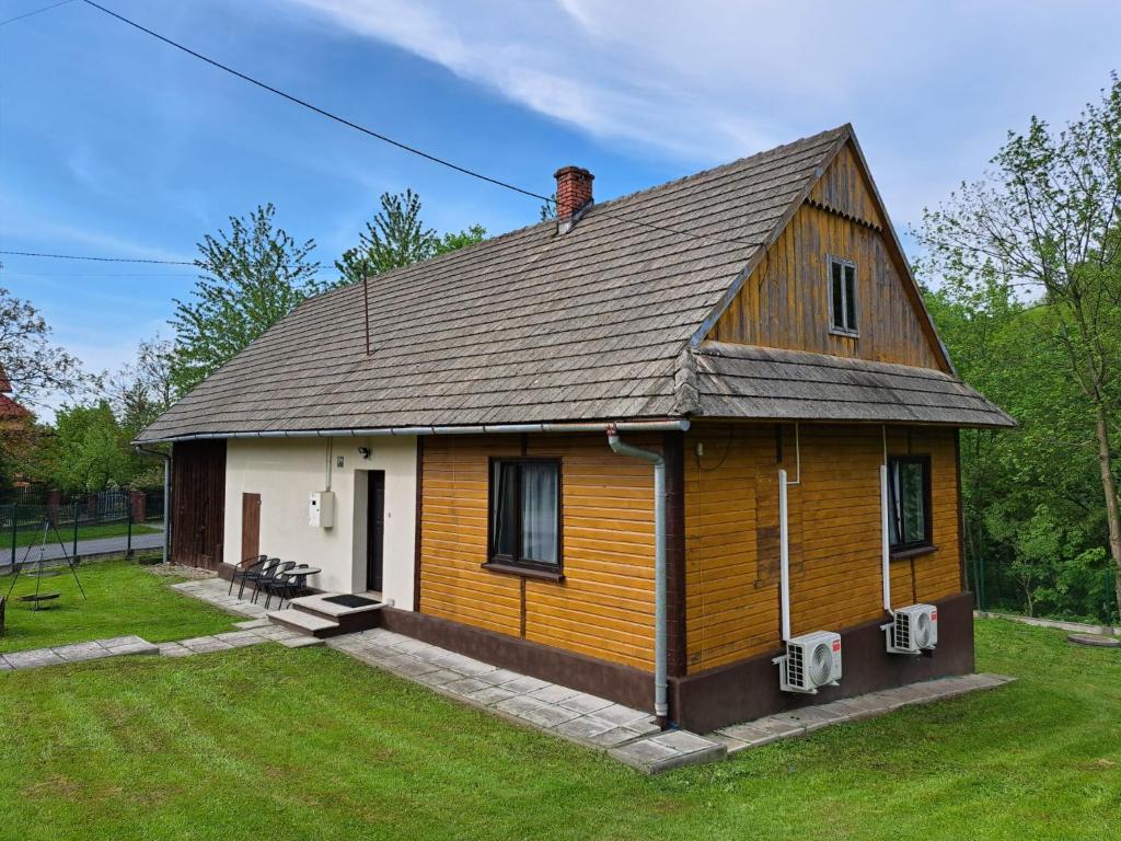 a large wooden house with a roof at Domek nad Potokiem in Rzyki