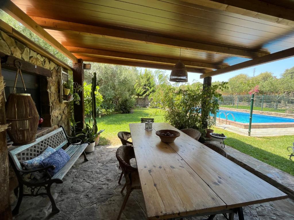 a wooden table and chairs on a patio with a pool at Chalet Valdevaqueros - Gran piscina y 5 min playa in Tarifa