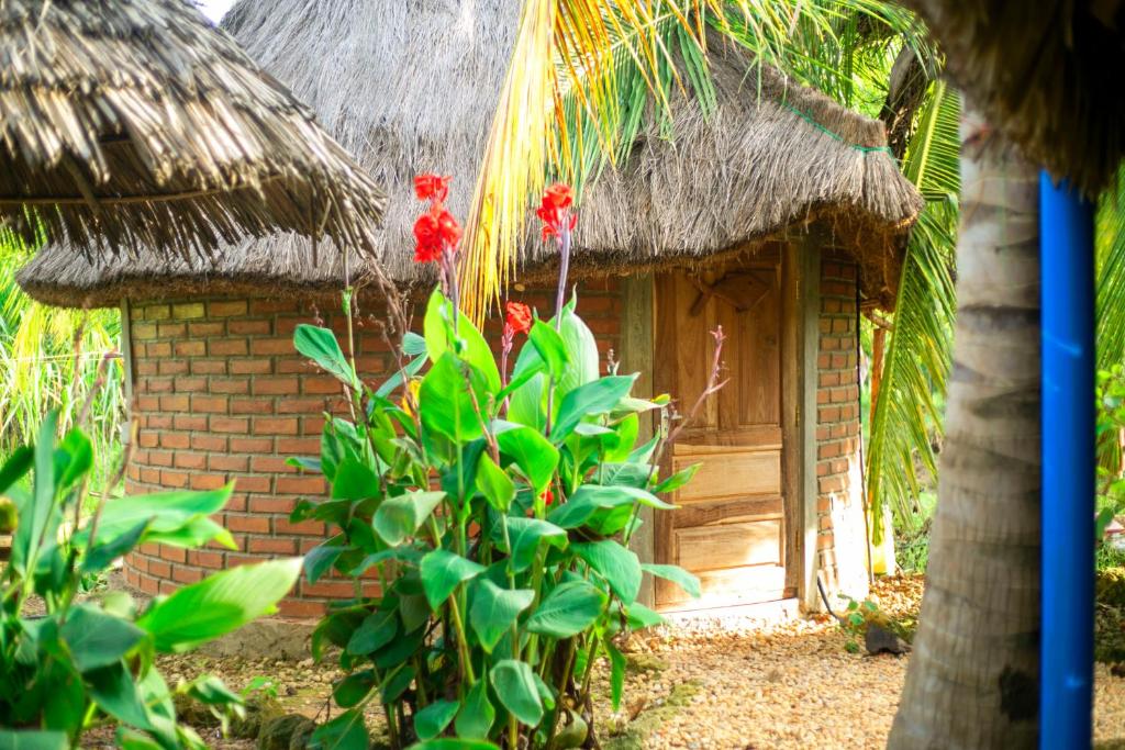 a small brick house with a thatch roof at AFLII Guest house in Mtwara