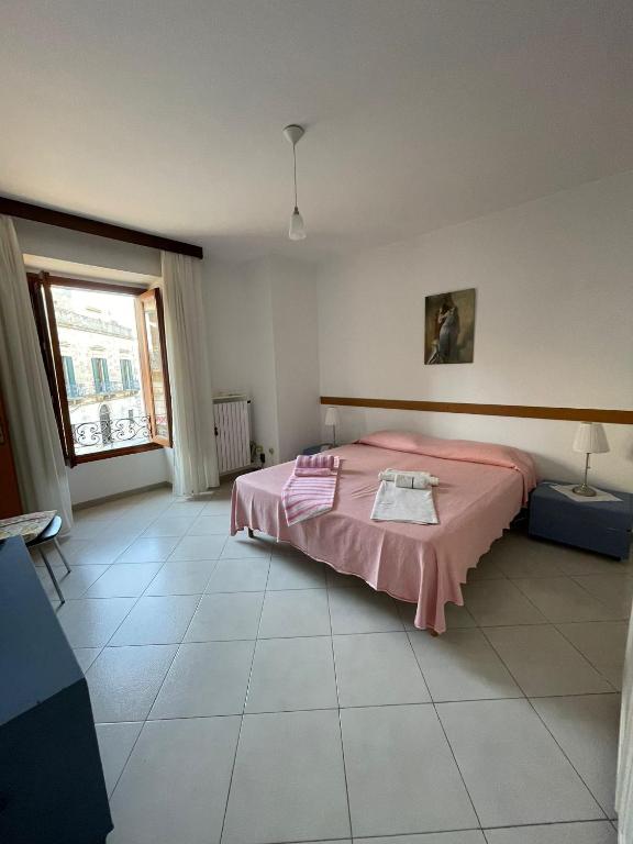 a bedroom with a pink bed and a large window at Dimora alla Villa in Ostuni