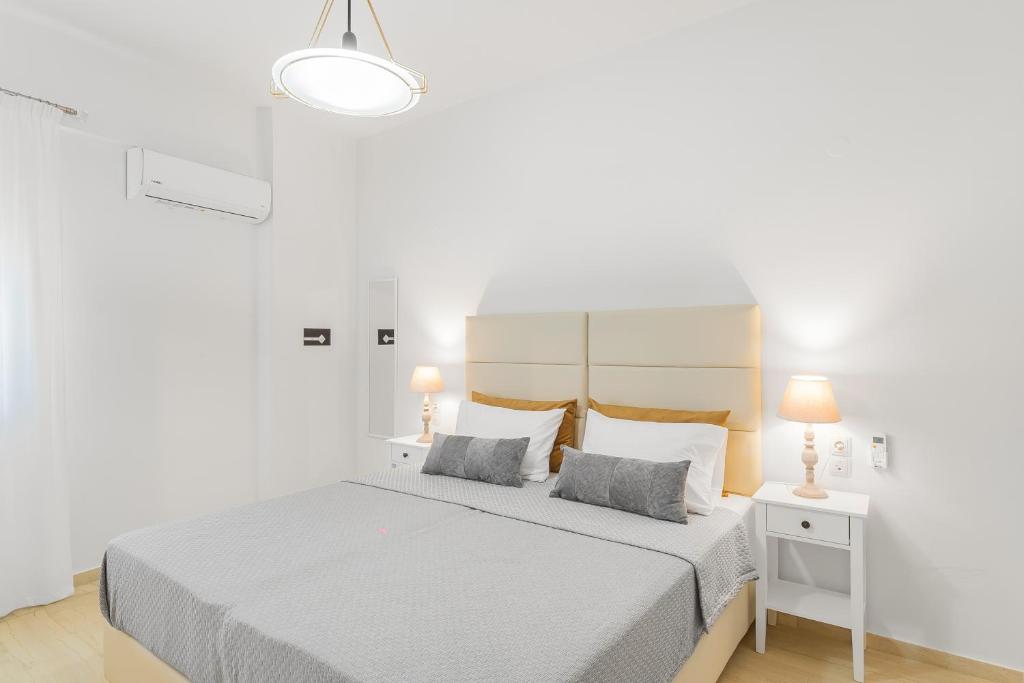 Maela Luxury Suite في ماليا: غرفة نوم بيضاء بسرير ومصباحين