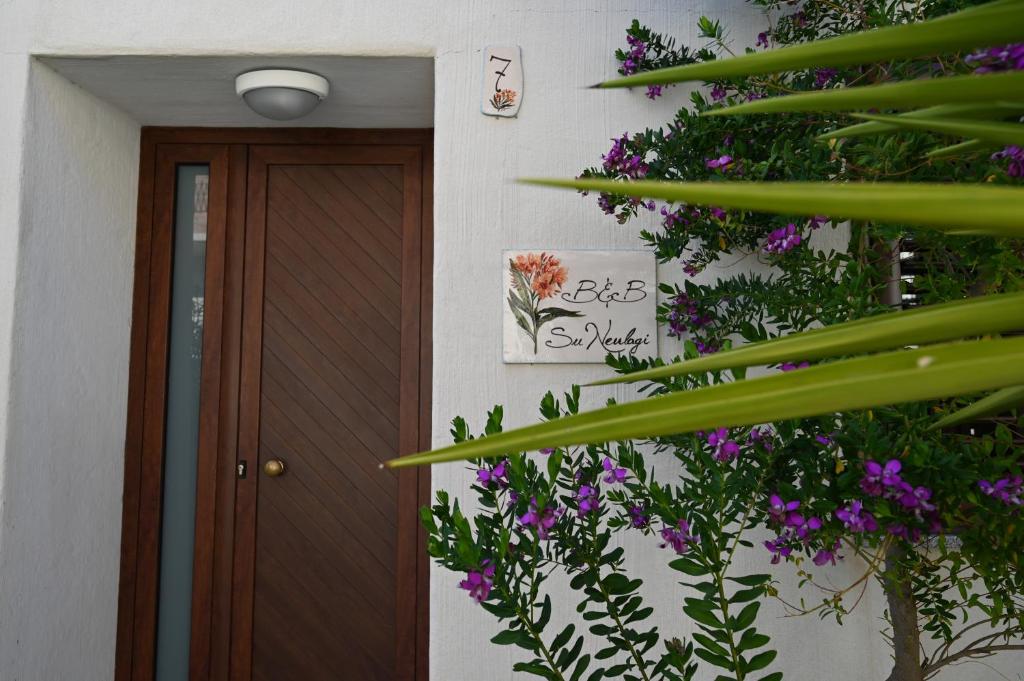 a house with a door and some purple flowers at B&B Su Neulagi in Triei