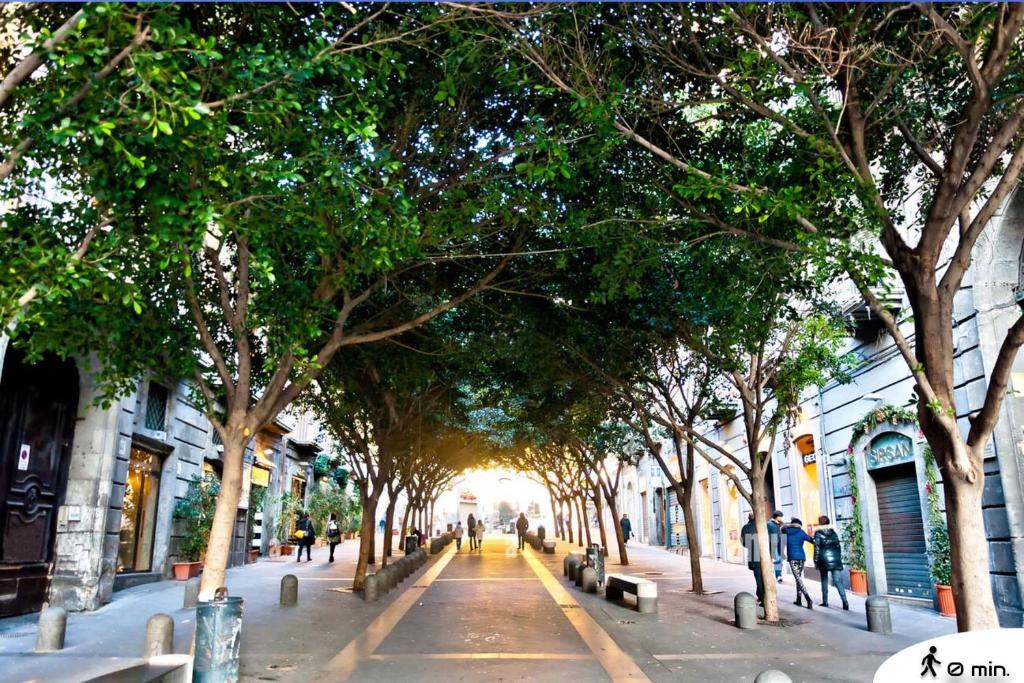 a street lined with trees and people walking down a street at Room&Chiaia in Naples