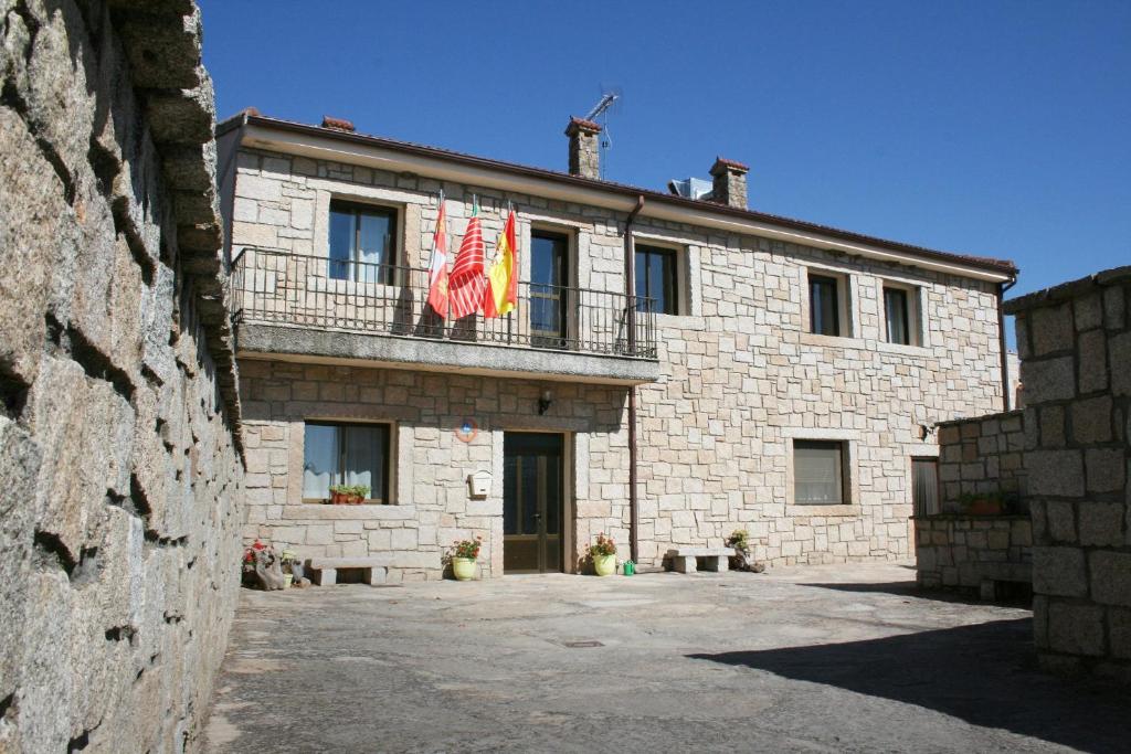 a stone building with two flags on a balcony at Albergue Rural La Rueca, Fariza 