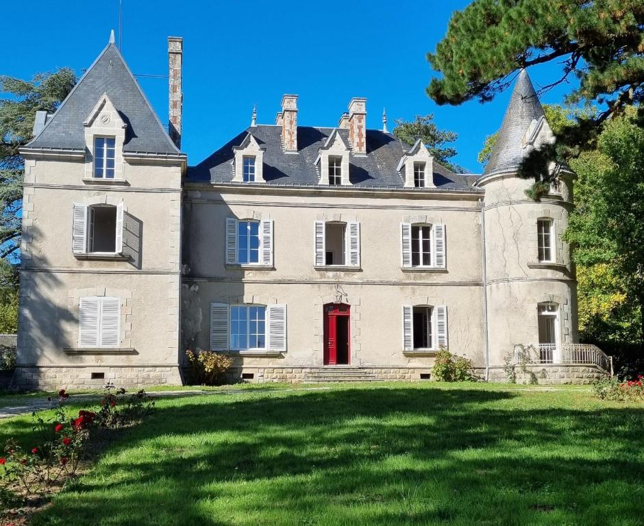un vieux château avec une porte rouge sur une pelouse dans l'établissement Chambres d'hôtes Château de Saint Etienne du Bois, à Saint-Étienne-du-Bois