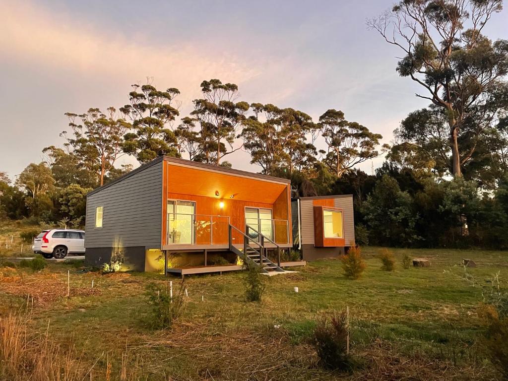 a tiny house in a field with a car at Bicheno Wildflower Sands coastal retreat in Bicheno