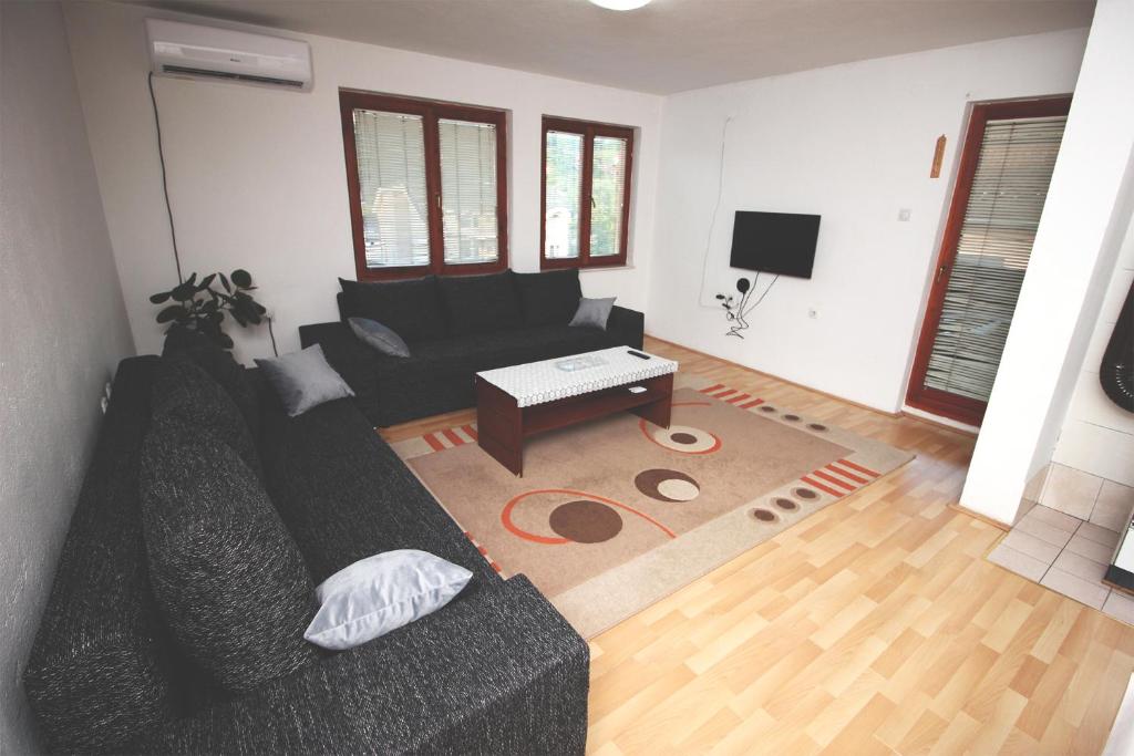 - un salon avec un canapé noir et une table dans l'établissement Apartman Komfor, à Banja Luka