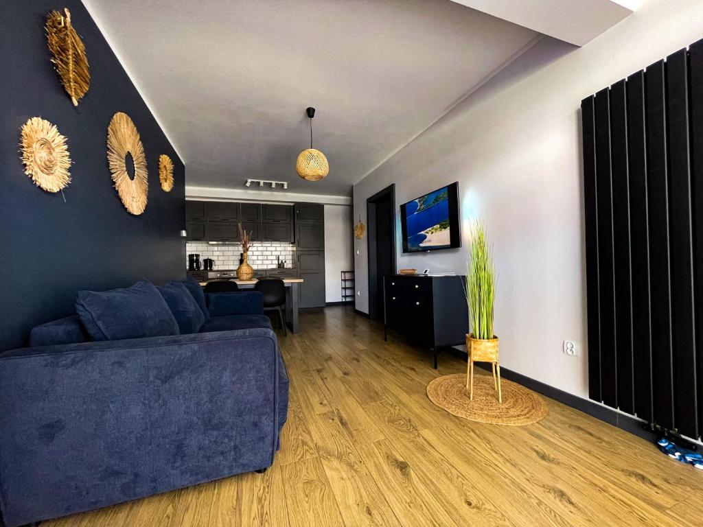 un salon avec un canapé bleu et une table dans l'établissement Apartament Cień Wiatru, à Darłowo