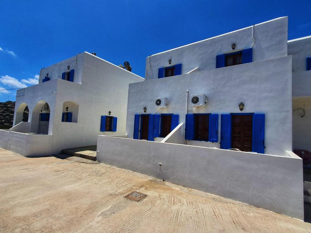a white house with blue doors on a building at Galini Apartments Sikinos Travel in Sikinos