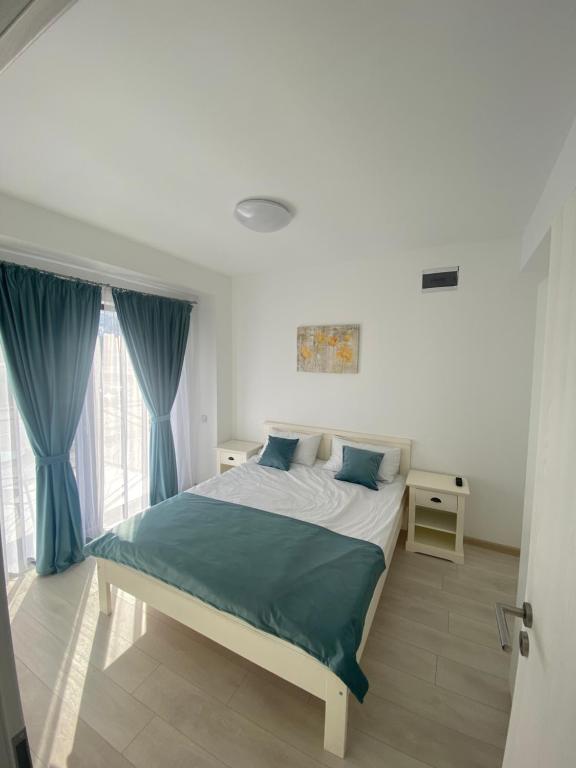 バイレ・フェリクスにあるApartament Oanaのベッドルーム1室(青いカーテン付きの大型ベッド1台付)